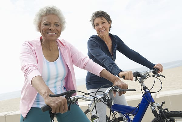 Two senior women riding bicycles on a beach